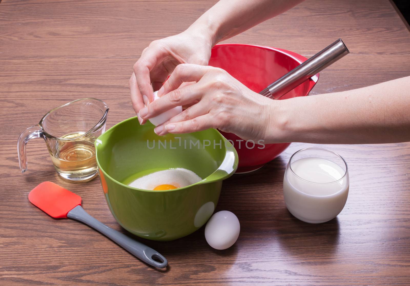 Woman breaking egg in a bowl to cook a homemade cake made from scratch