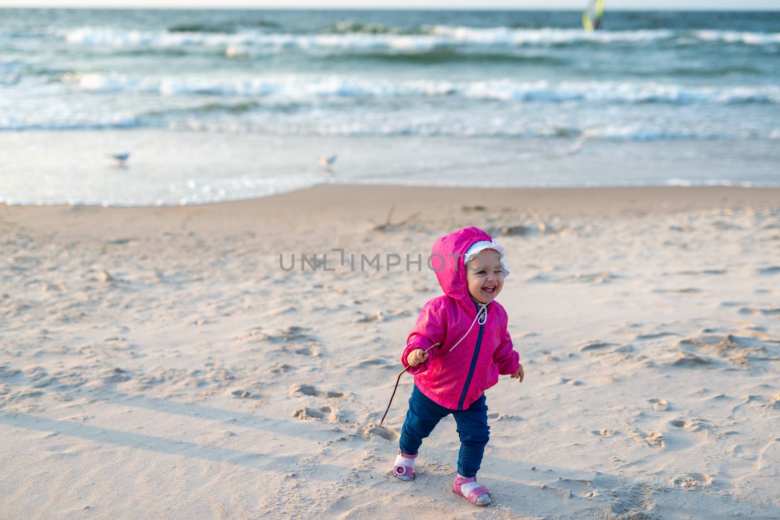 Adorable toddler girl on a sunny sand beach. Childhood
