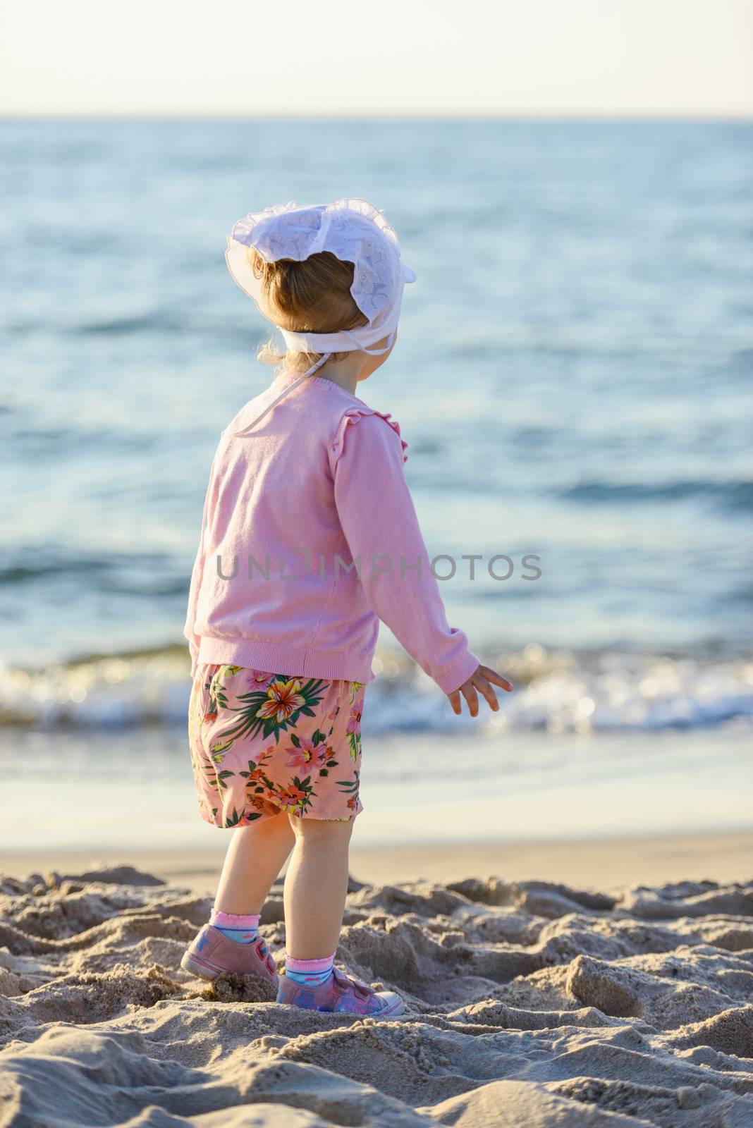 Adorable toddler girl on a sunny sand beach. Childhood