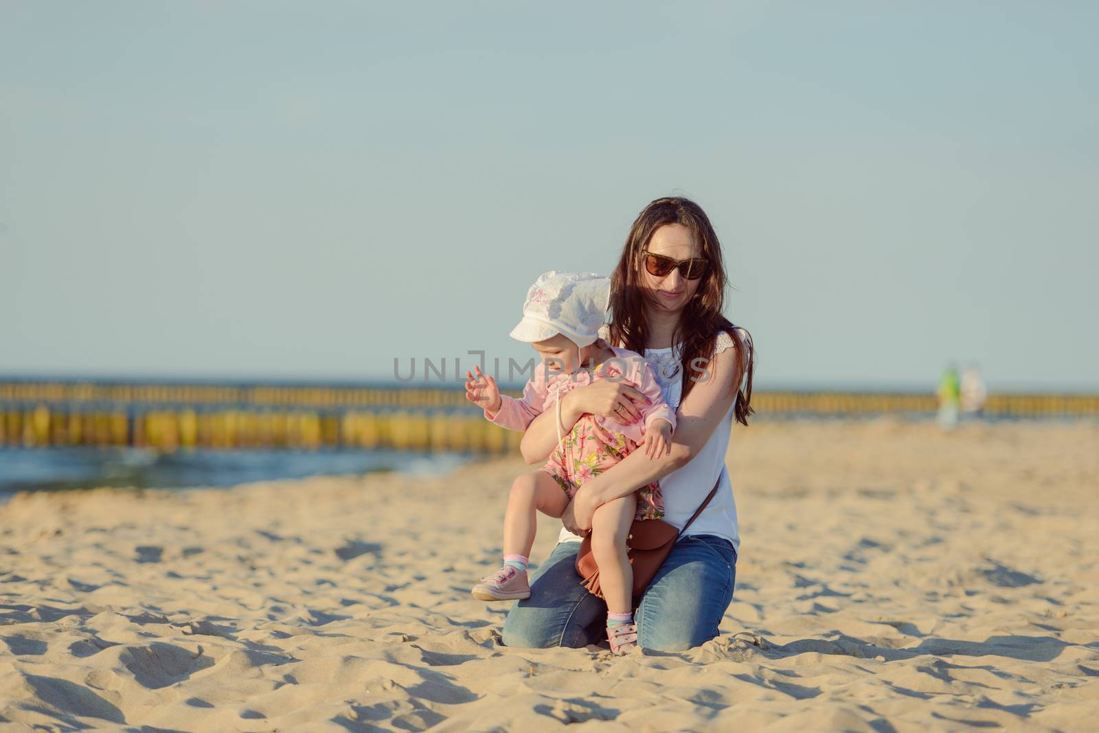 Mother and little daughter walking on the beach.