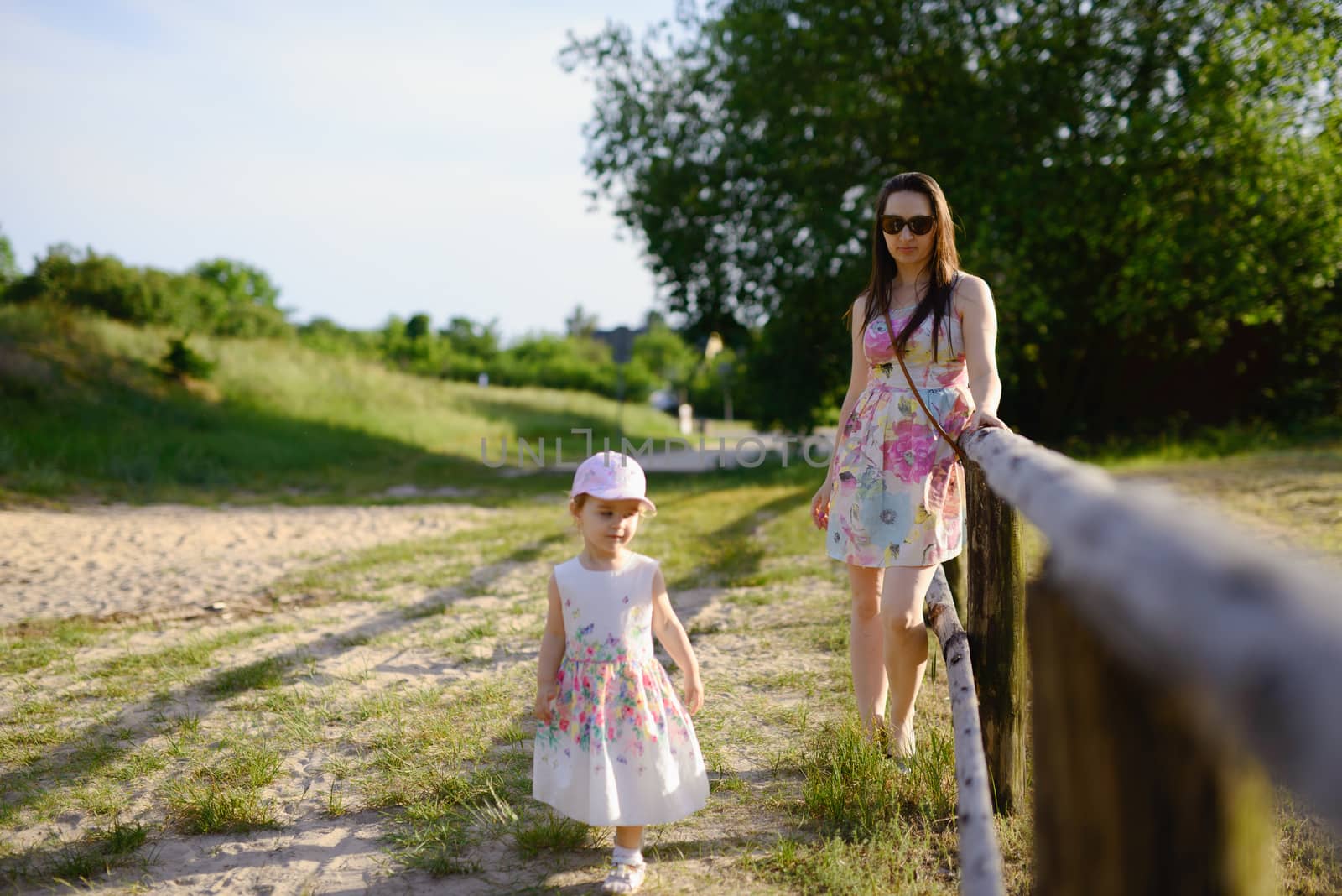 Happy mother and daughter in the park. Beauty nature scene with family outdoor lifestyle. Happy family resting together on the green grass, having fun outdoor. Happiness and harmony in family life.