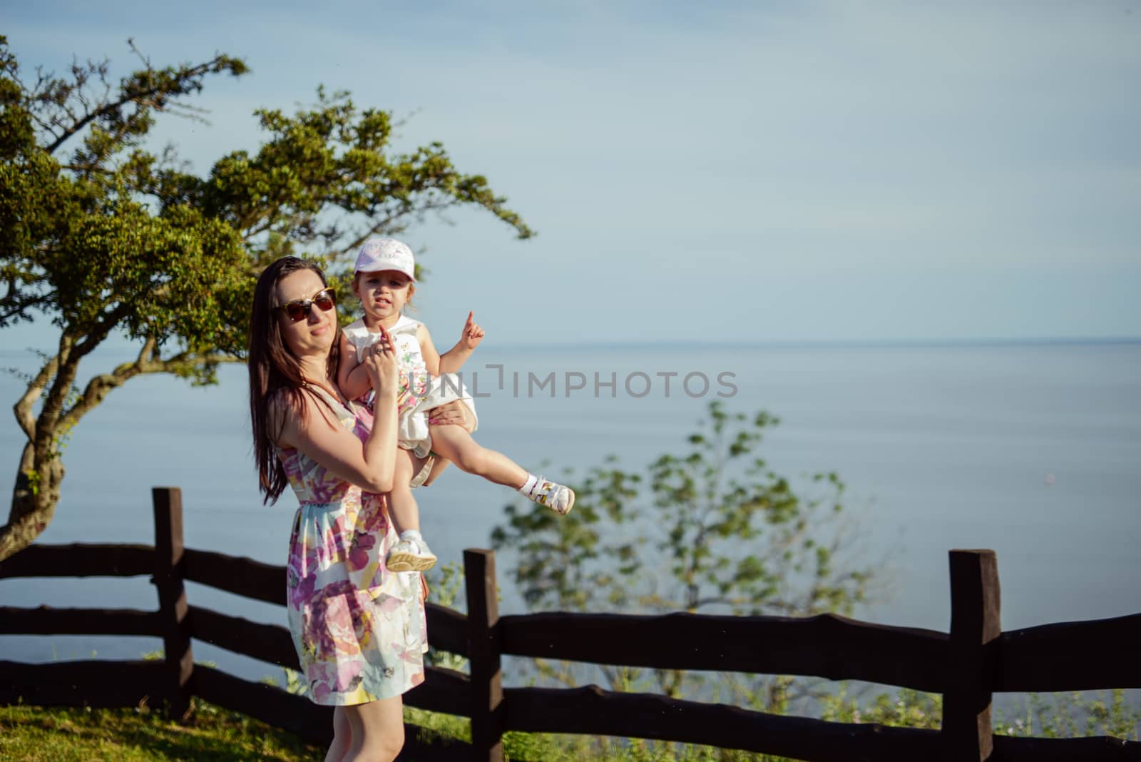 Happy mother and daughter in the park. Beauty nature scene with family outdoor lifestyle. Happy family resting together on the green grass, having fun outdoor. Happiness and harmony in family life.