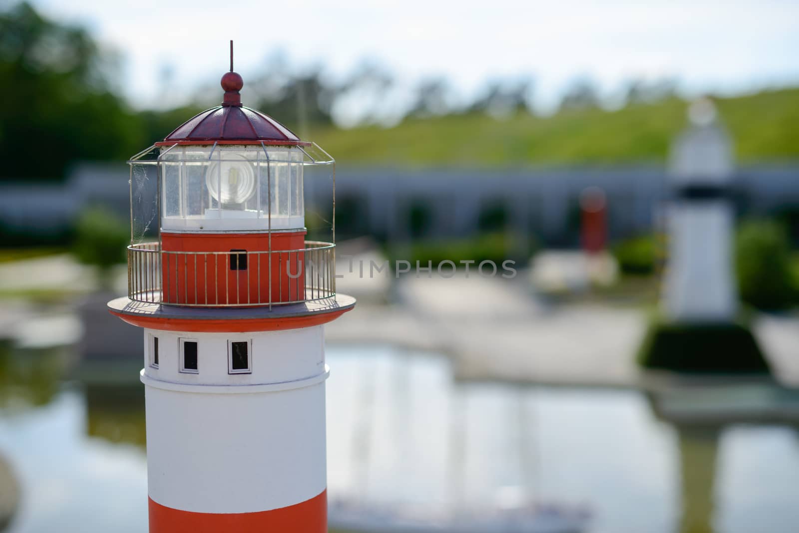 toy lighthouse, blue toy lighthouse and yellow sailboat with sand beach background