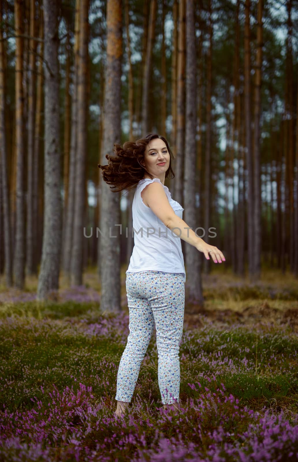 a photo of woman in the forest where the purple heather blooms. copy space