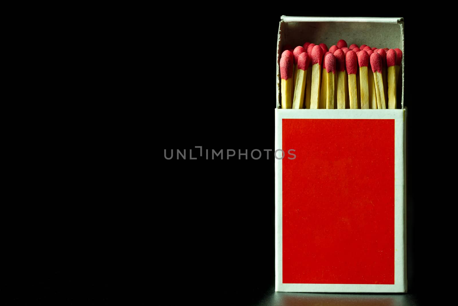 Matches stick in red paper box on black background. Closeup and copy space.