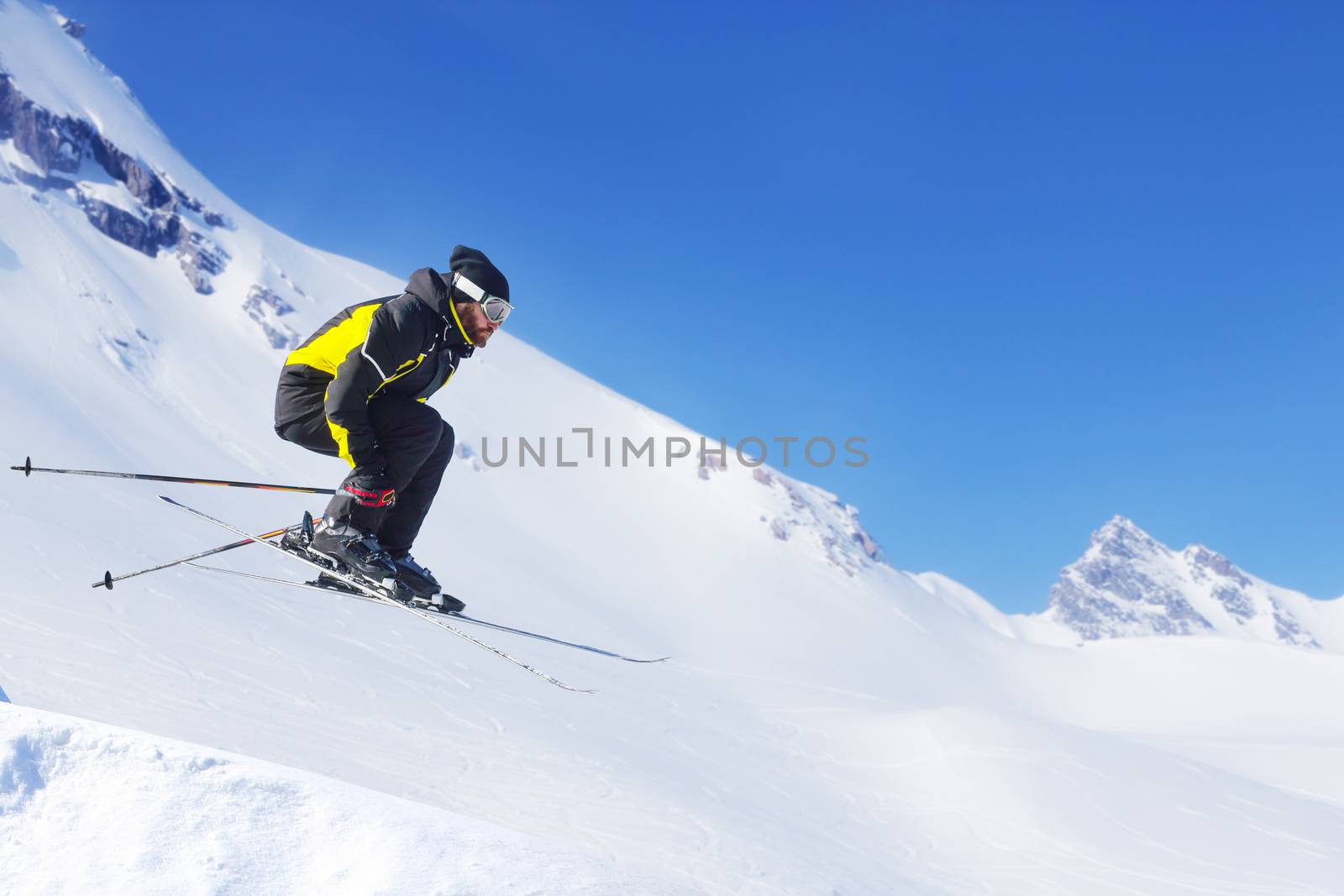 Jumping skier at jump with alpine high mountains