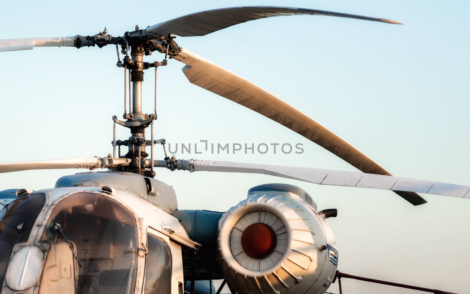 engine and propeller blades of an old vintage helicopter against a blue sky