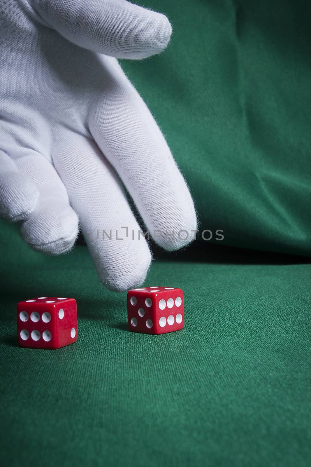 Hand in a white glove throwing red dice on the table