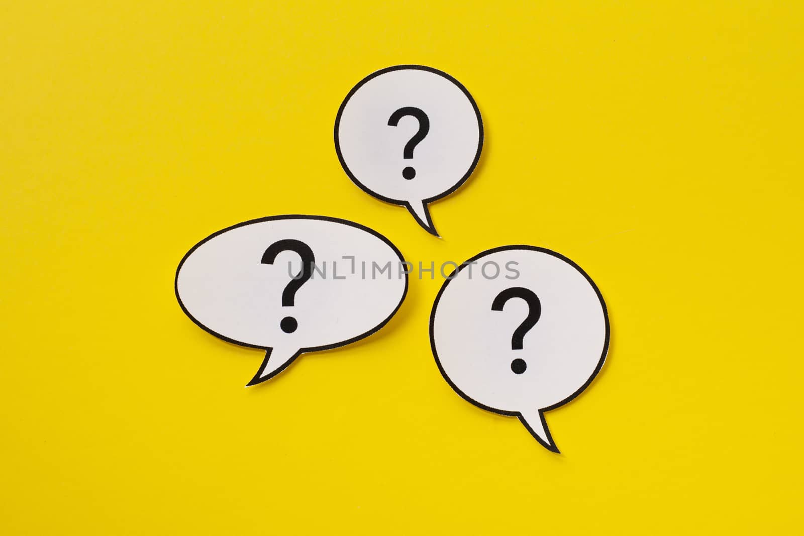 Three different shaped speech bubbles with question marks inside over a bright yellow background arrange in the centre
