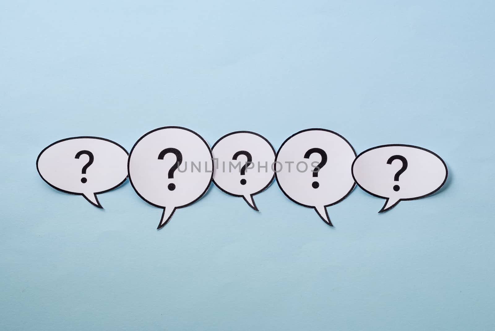 Line of question marks in speech bubbles of assorted shapes over a blue background with copy space above and below