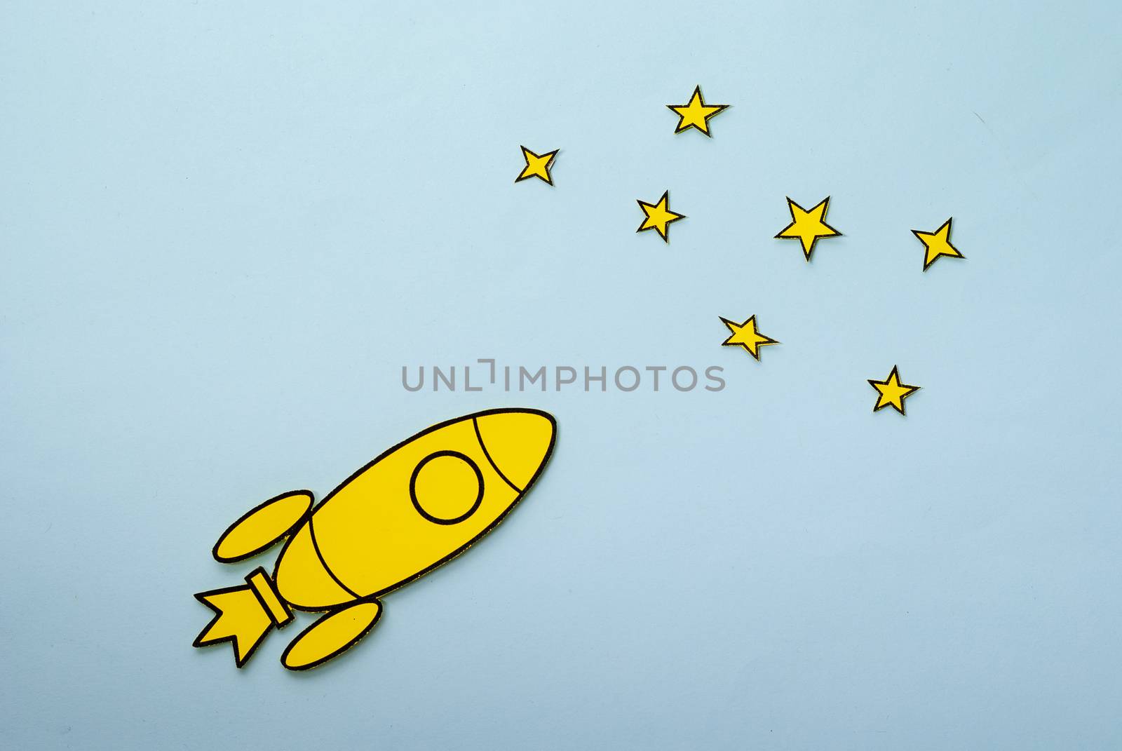 Yellow cartoon rocket flying through space towards the stars in a concept of success and achievement over a blue background with copy space