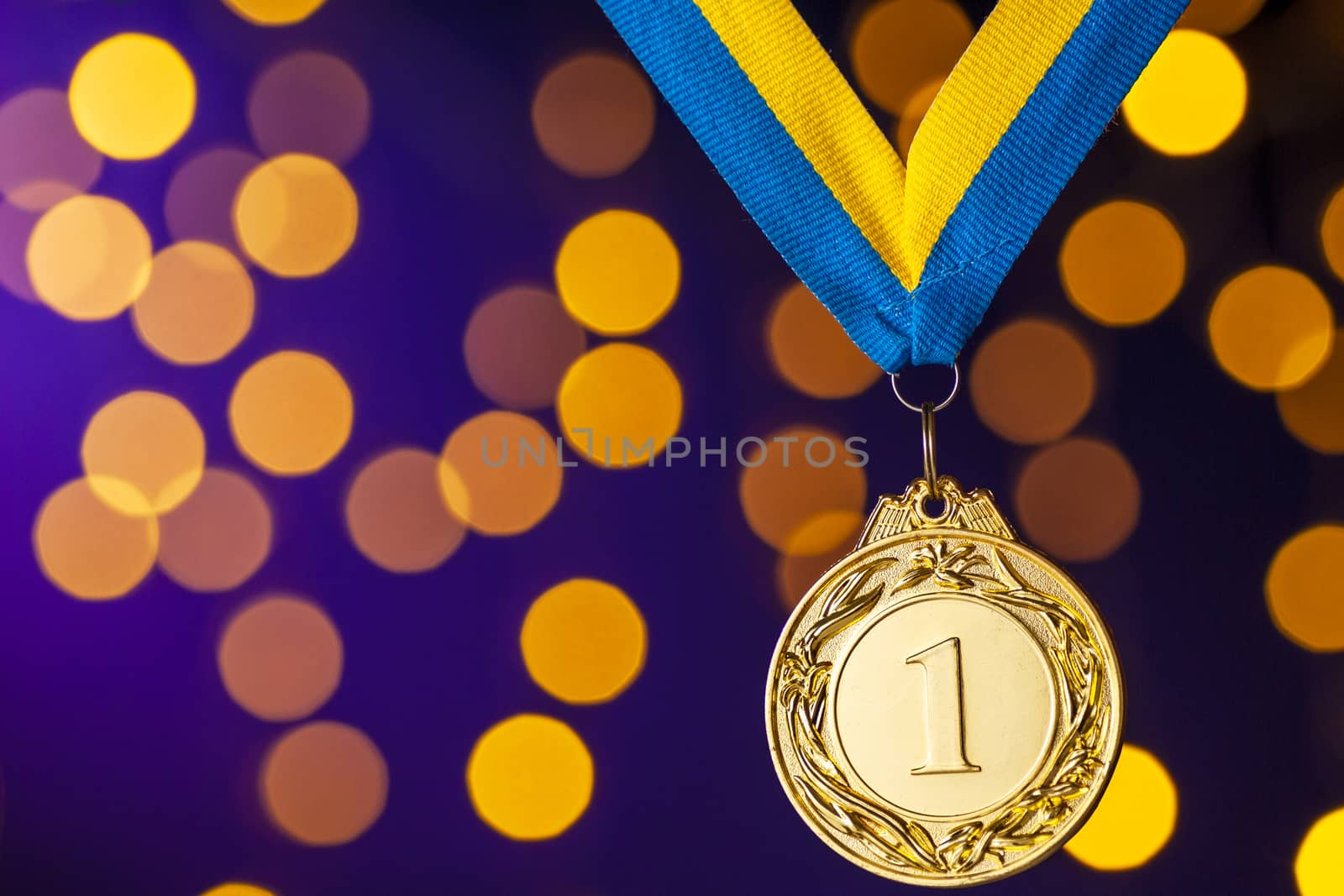 Gold champion or winners medallion on a ribbon over a purple background with festive golden bokeh of party lights to celebrate the win