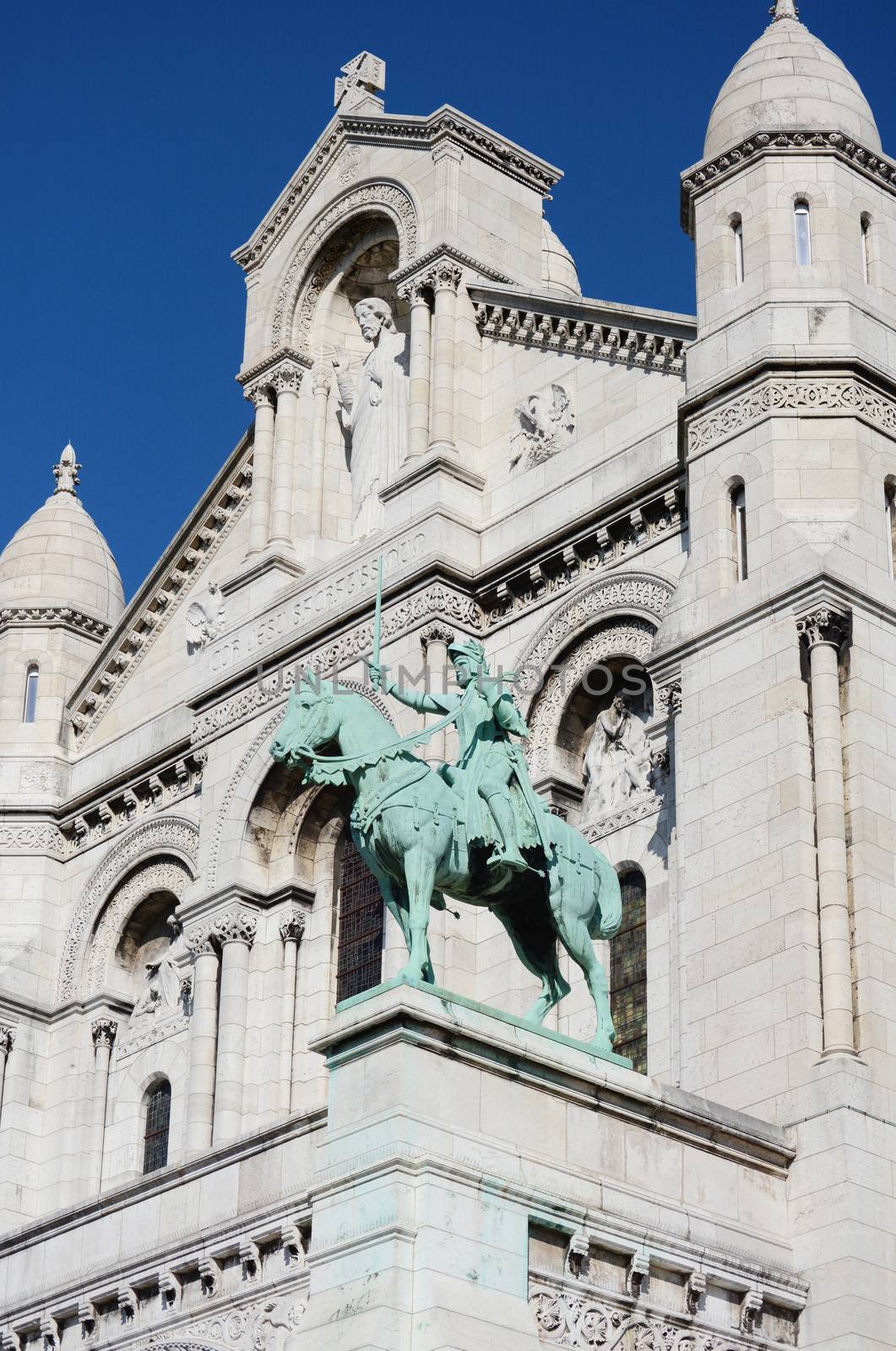 Joan of Arc bronze equestrian statue on the facade of the Sacre Coeur basilica, with the limestone architecture of the church beyond