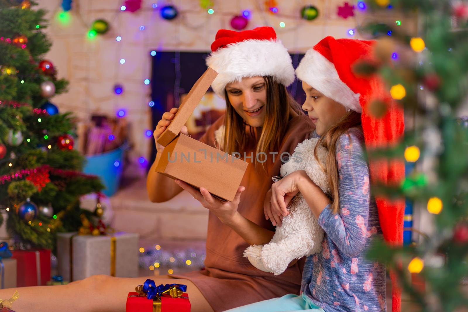 Mom and girl with interest look into the open New Year's gift