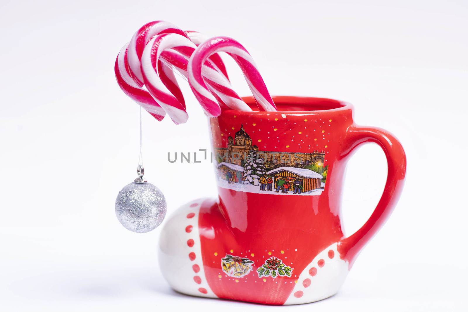 Concept of christmas drink on a white background.Red and white candy canes in red cup.