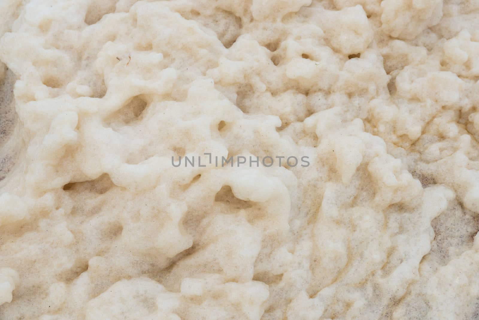 Closeup shot of foam on a beach. The foam can have natural reasons or can be a result of the sea water pollution.