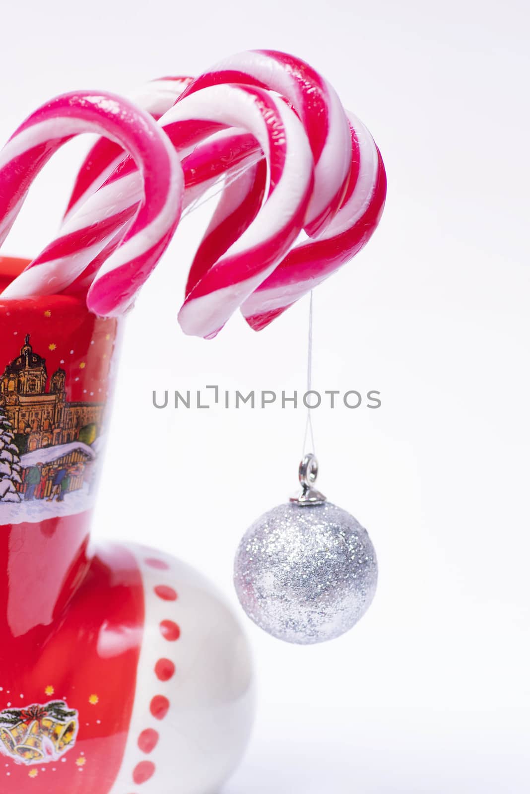 Traditional Christmas candies, lollipop, sticks minimalistic design.New Year candy canes in a red cup on a white background. New Year concept. Sweet candy canes.