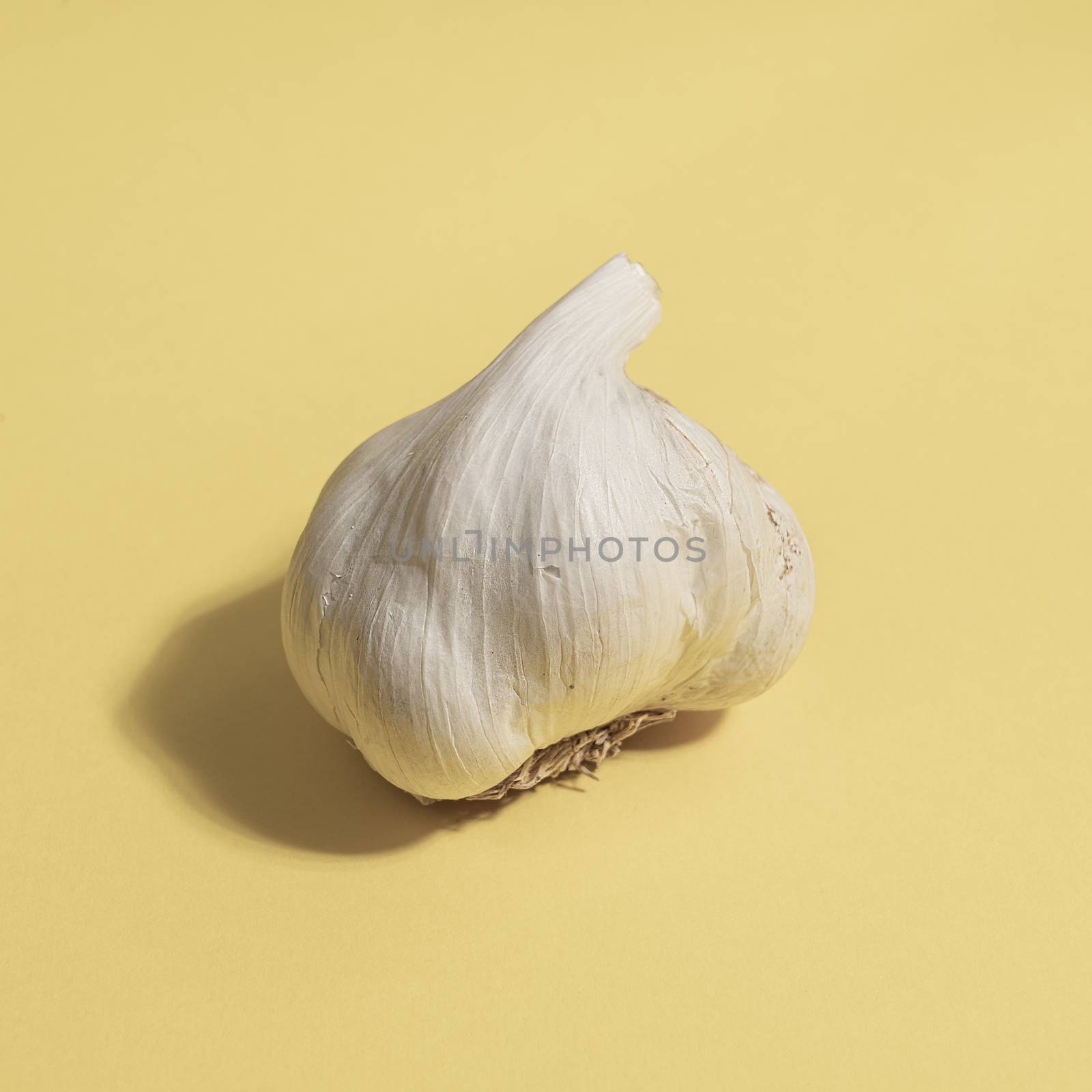 A garlic bulb on a yellow surface