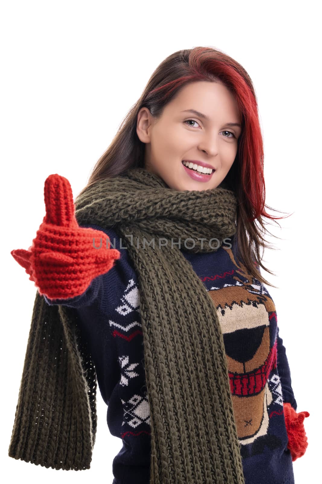 Smiling young girl in warm winter clothes giving thumbs up by Mendelex