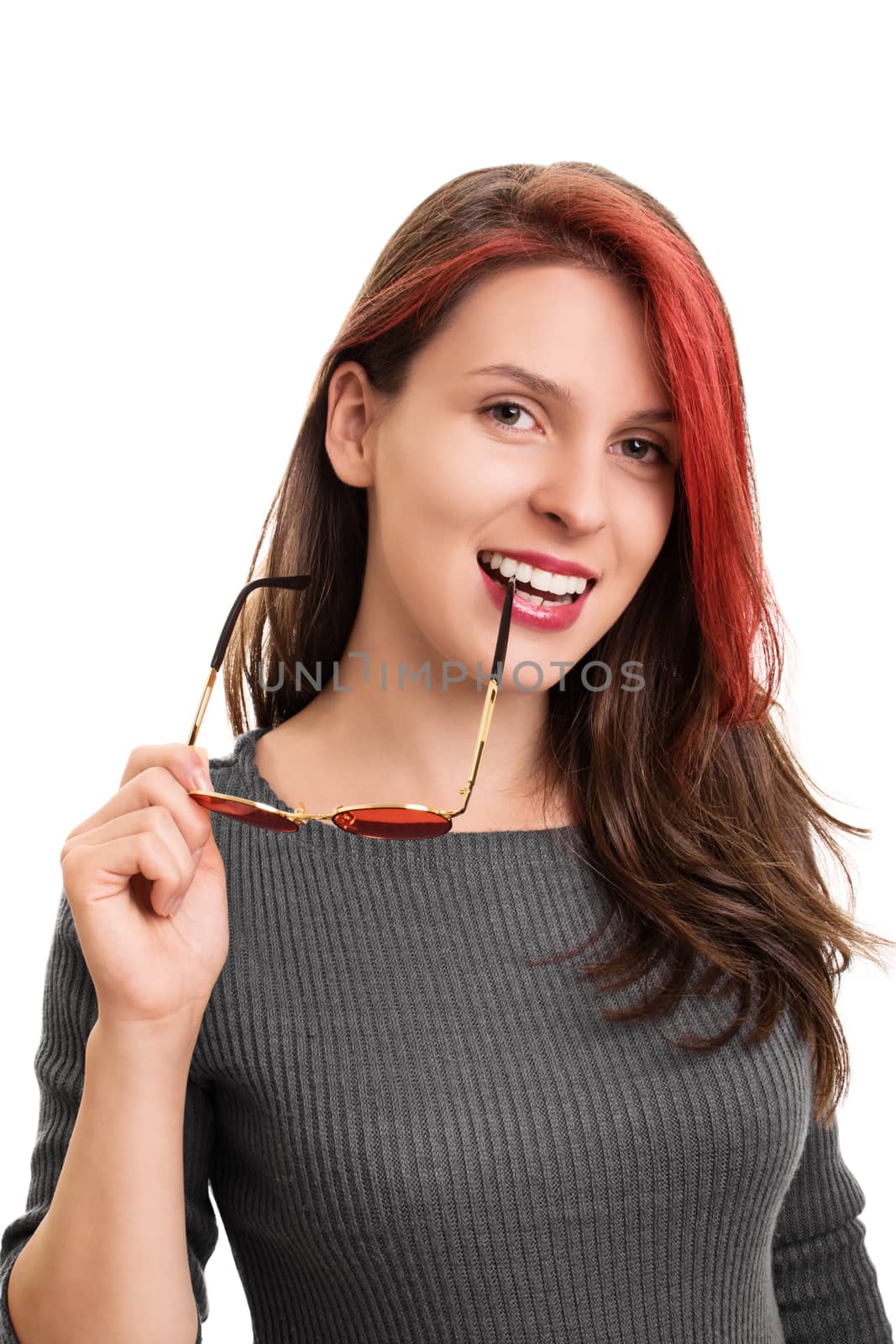 Close up portrait of a smiling beautiful young woman biting the shackle of sunglasses, looking at the camera, isolated on white background. Beautiful smiling girl with a shackle of sunglasses in her mouth.