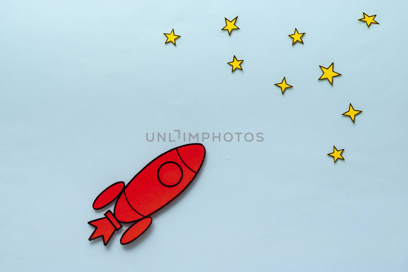 Colorful red rocket zooming through space reaching for the stars in a concept of ambition and success over a blue background with copy space