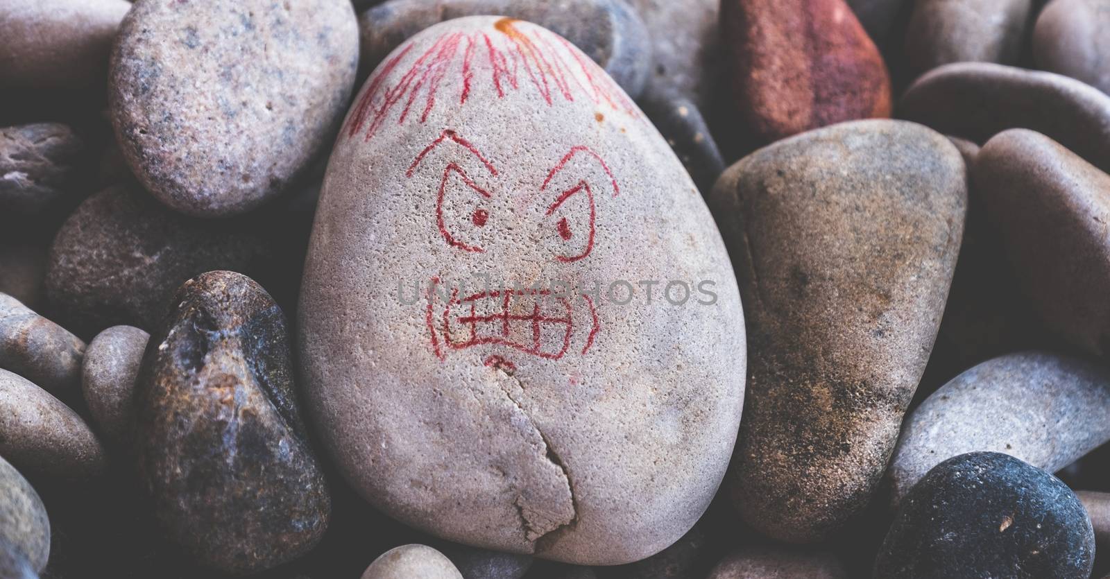 angry nasty face draw on stones for anger attack in lonely mind nervous neurology horizontal by LucaLorenzelli