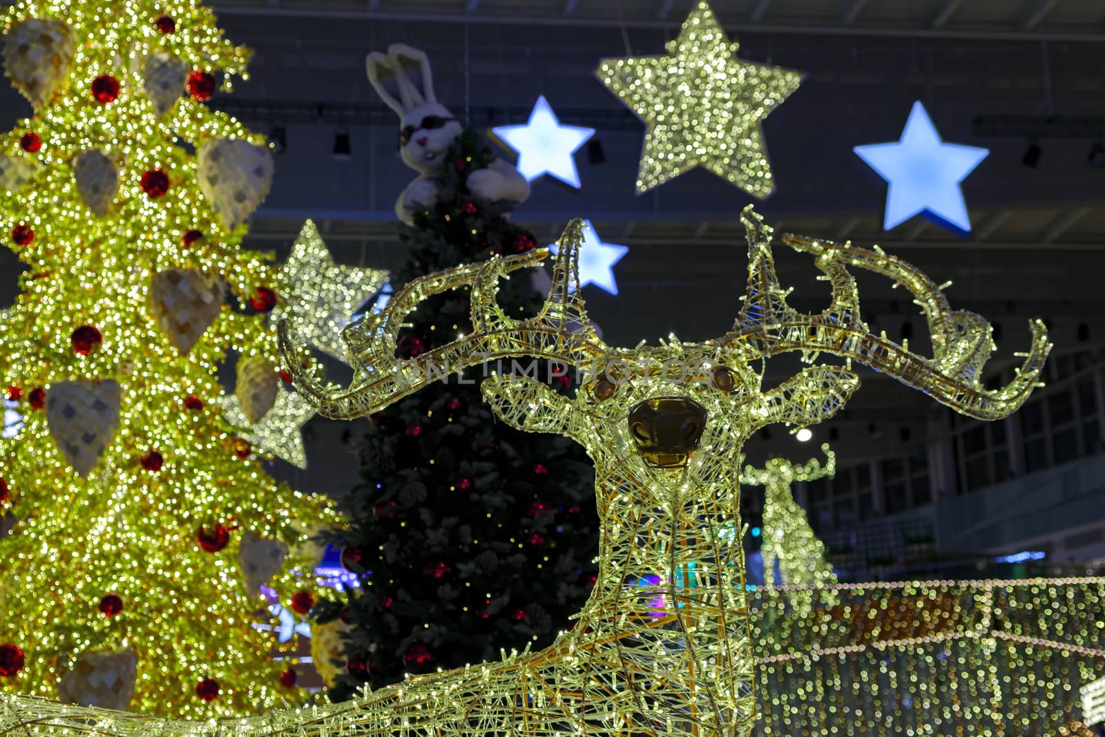 Bright festive Christmas illumination. Glowing figure of a deer against the background of a Christmas tree.