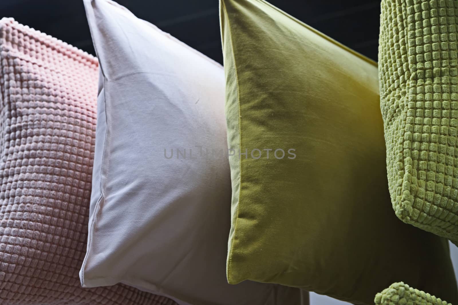 Green, white, pink square pillows are shot close-up. Colorful background of soft pillows.