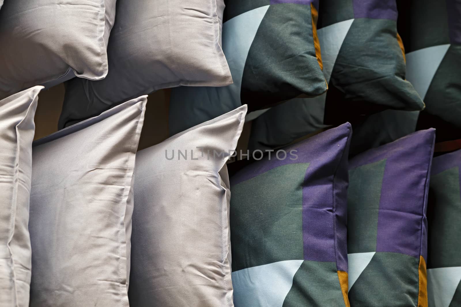 Green, white, pink square pillows are shot close-up. Colorful background of soft pillows.