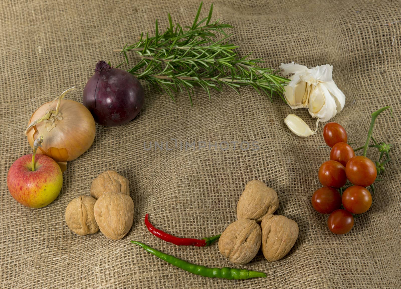 frame of different ingredients foods vegetables and herbs with space in the middel for text on jute background