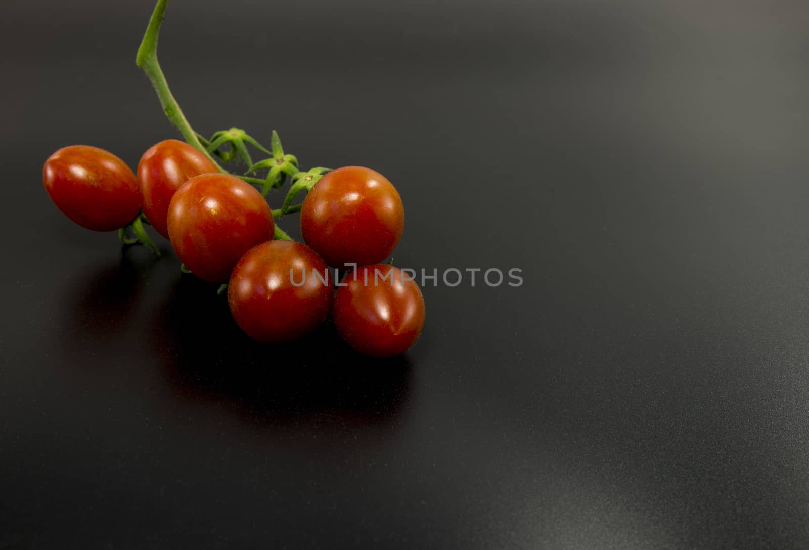 fresh red cherry tomatoes on black background