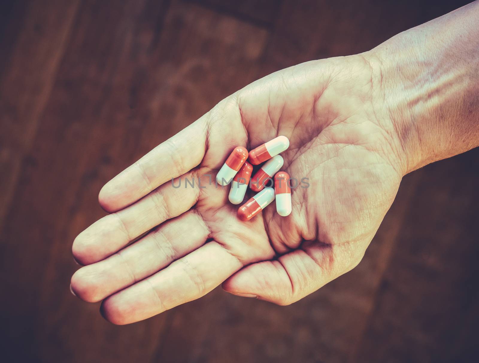 Retro Style Healthcare Image Of Pills Or Tablets Or Capsules In A Person's Hand