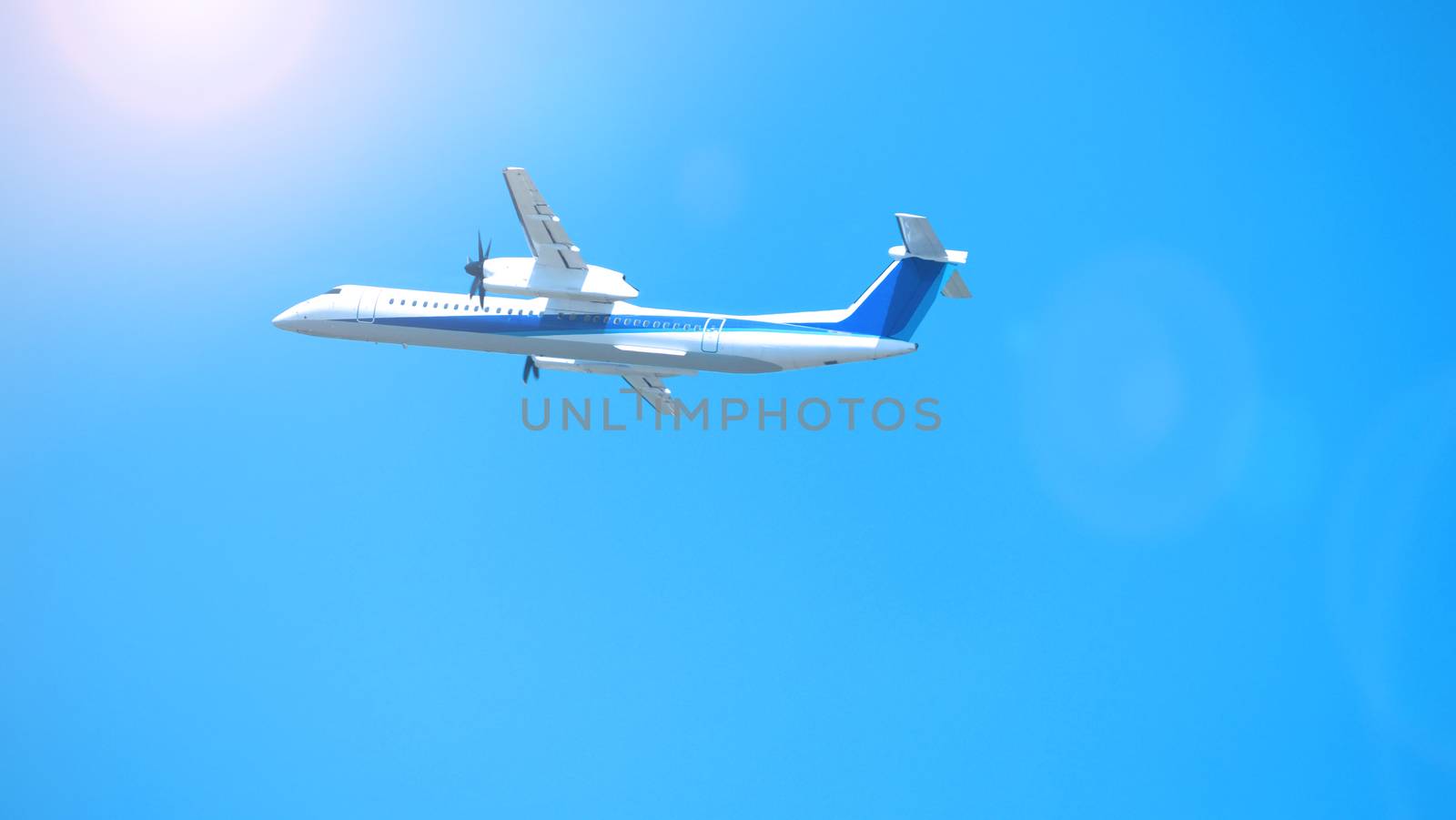 Airplane taking off to the blue sky from international airport runway in Sapporo Hokkaido Japan and have sun light flare to camera and shoot from uprisen or low angle view.