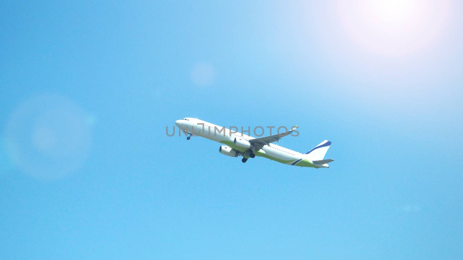 Airplane taking off to the blue sky from international airport runway in Sapporo Hokkaido Japan and have sun light flare to camera and shoot from uprisen or low angle view.