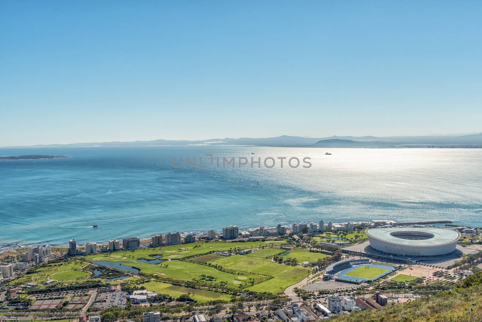 An aerial view of Green Point in Cape Town as seen from Signal Hill. The Cape Town Stadium and other sport facilities are visible. Robben Island is visible