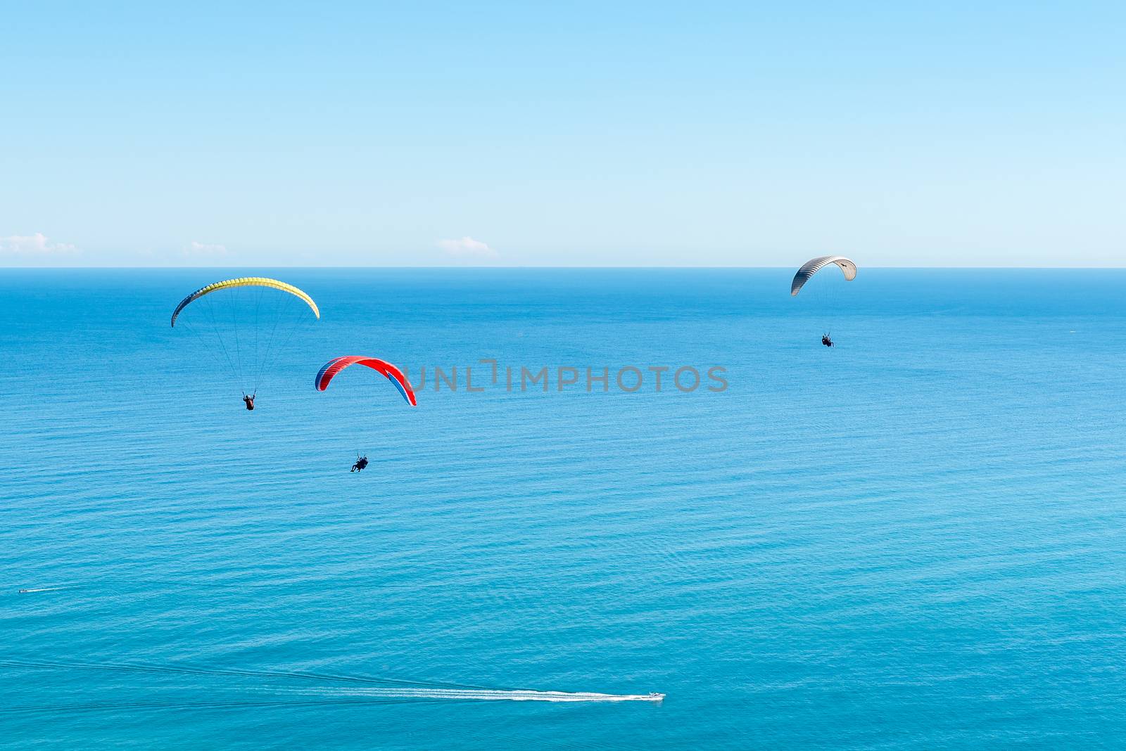 Three tandem paragliders above Sea Point after launch from Signal Hill in Cape Town in the Western Cape Province. Speedboats are visible below