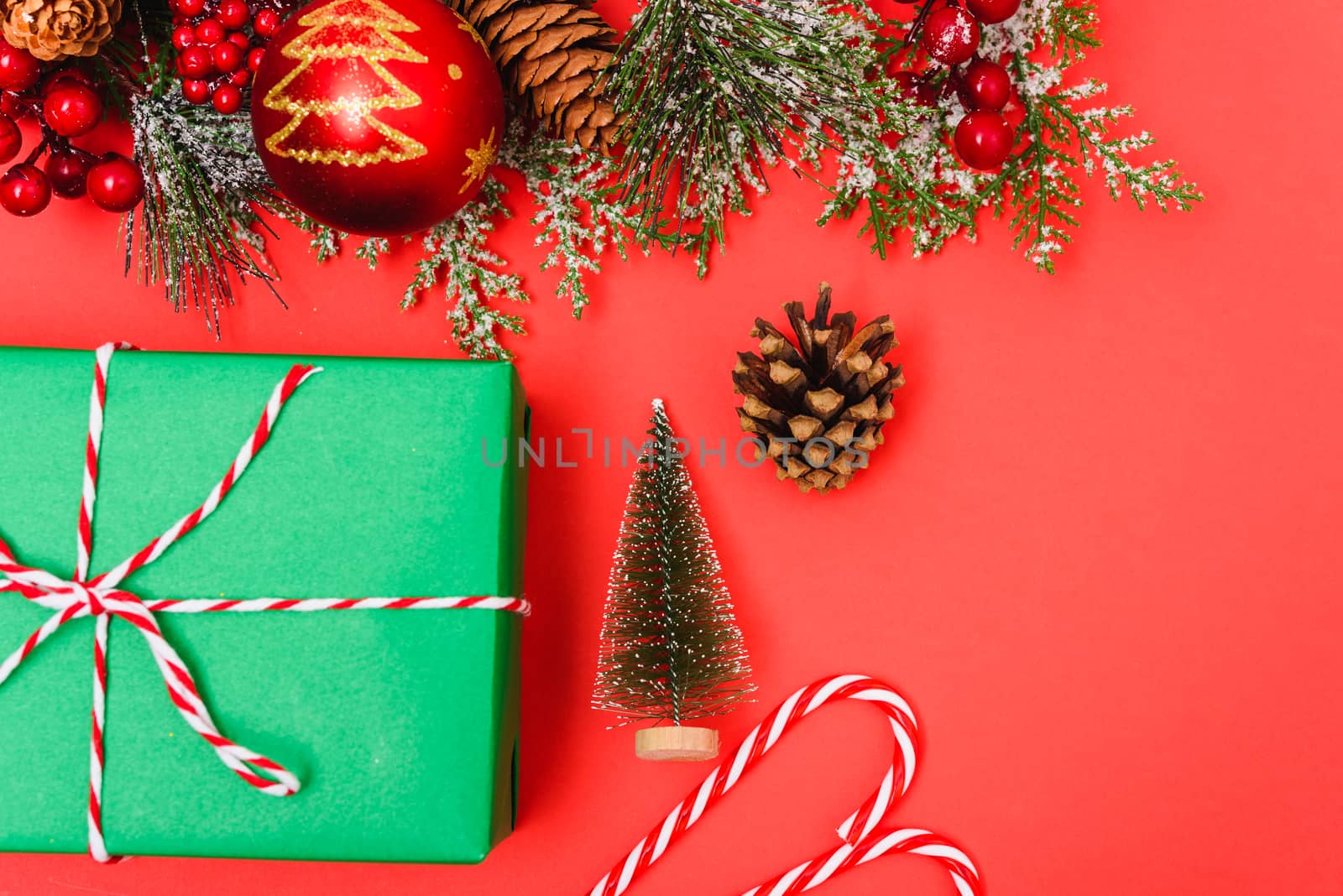 Christmas green gift box and decorations, fir tree branches on red background. Merry Christmas concept. With Copy space for text