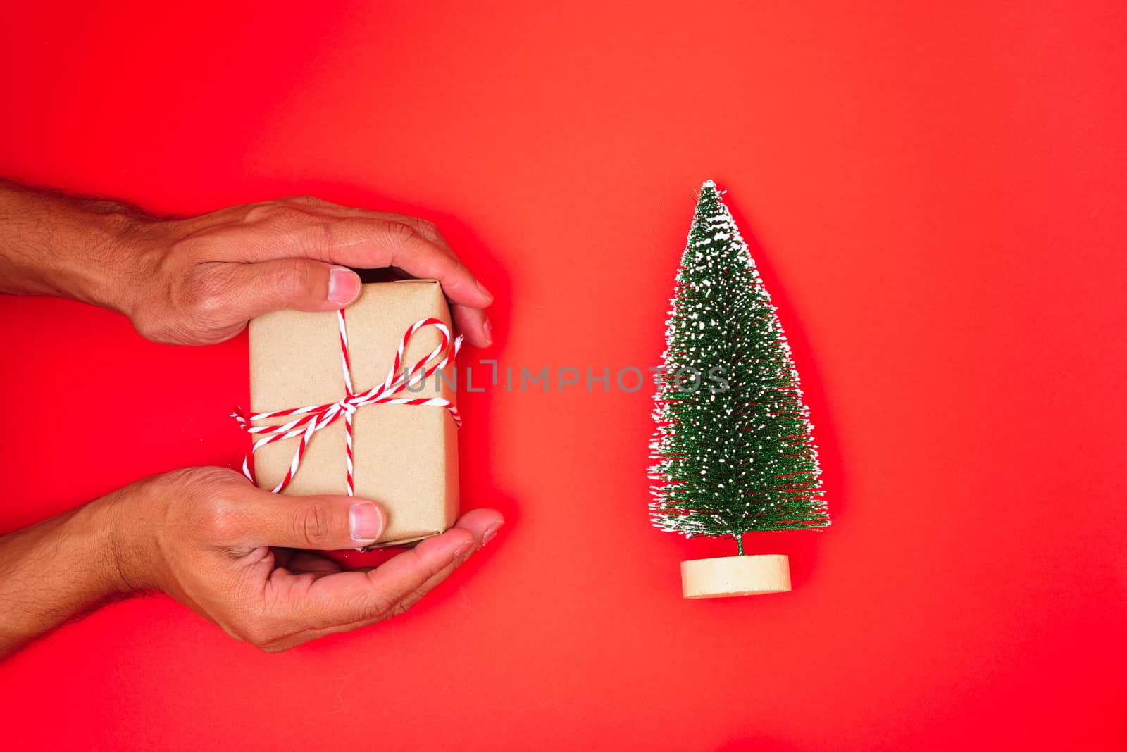 Happy New Year and Christmas 2020 or valentine day, top view hands with Brown gift box on red background with copy space for your text