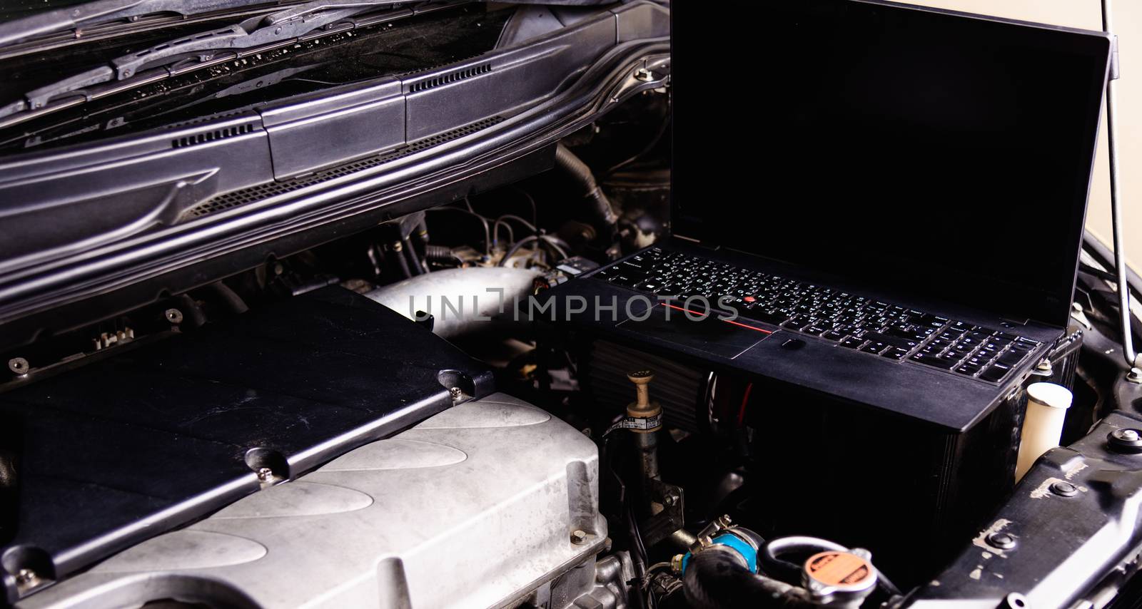 Laptop computer on car mechanic engine for service by Sorapop