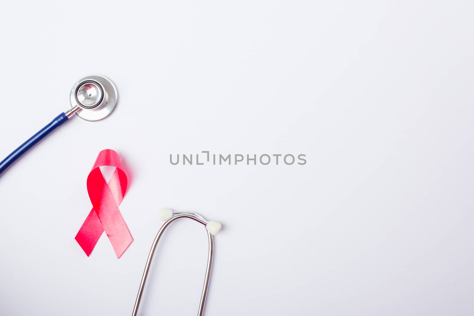 Breast cancer month concept, flat lay top view, pink ribbon and stethoscope on white background with copy space for your text