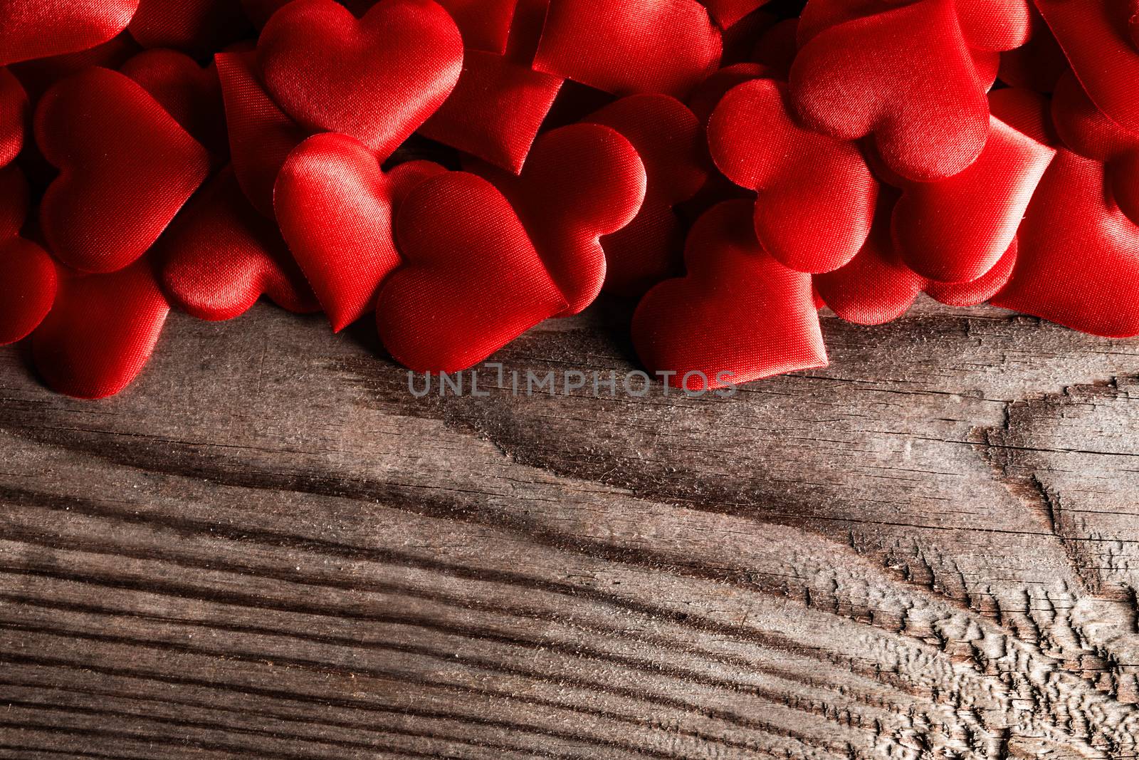 Valentine's day many red silk hearts on wooden background, love concept