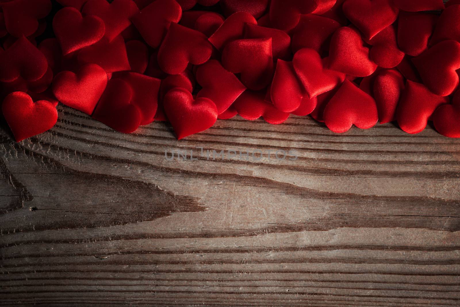 Valentine's day many red silk hearts on wooden background, love concept