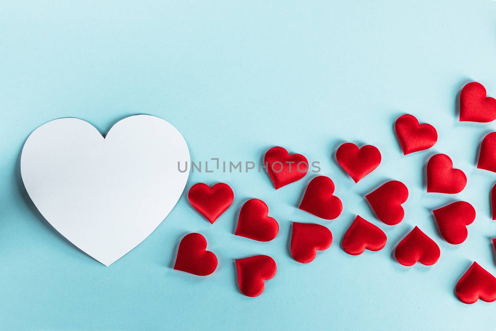 Valentine's day many red silk hearts and white heart shape card on blue paper background , border frame on red with copy space, love concept