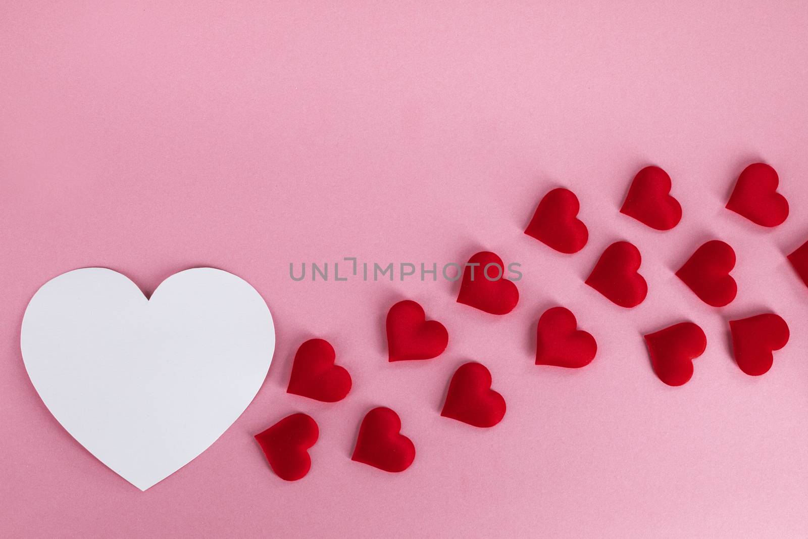 Valentine's day many red silk hearts and white heart shape card on pink paper background , border frame on red with copy space, love concept