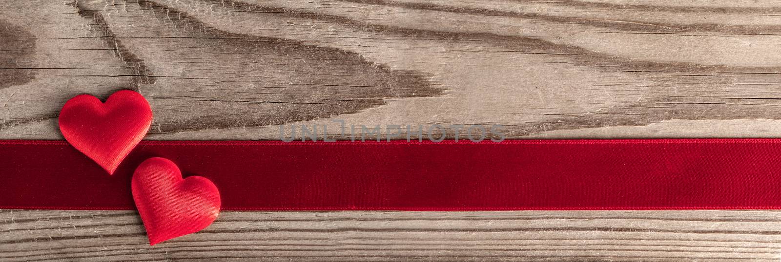 Valentine's day two red silk hearts and ribbon stripe on wooden background, love concept