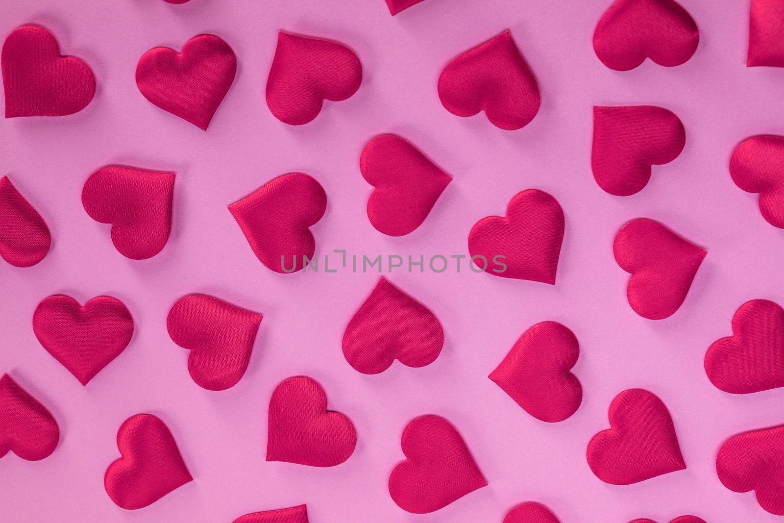 Valentine's day many red silk hearts on pink paper background, love concept