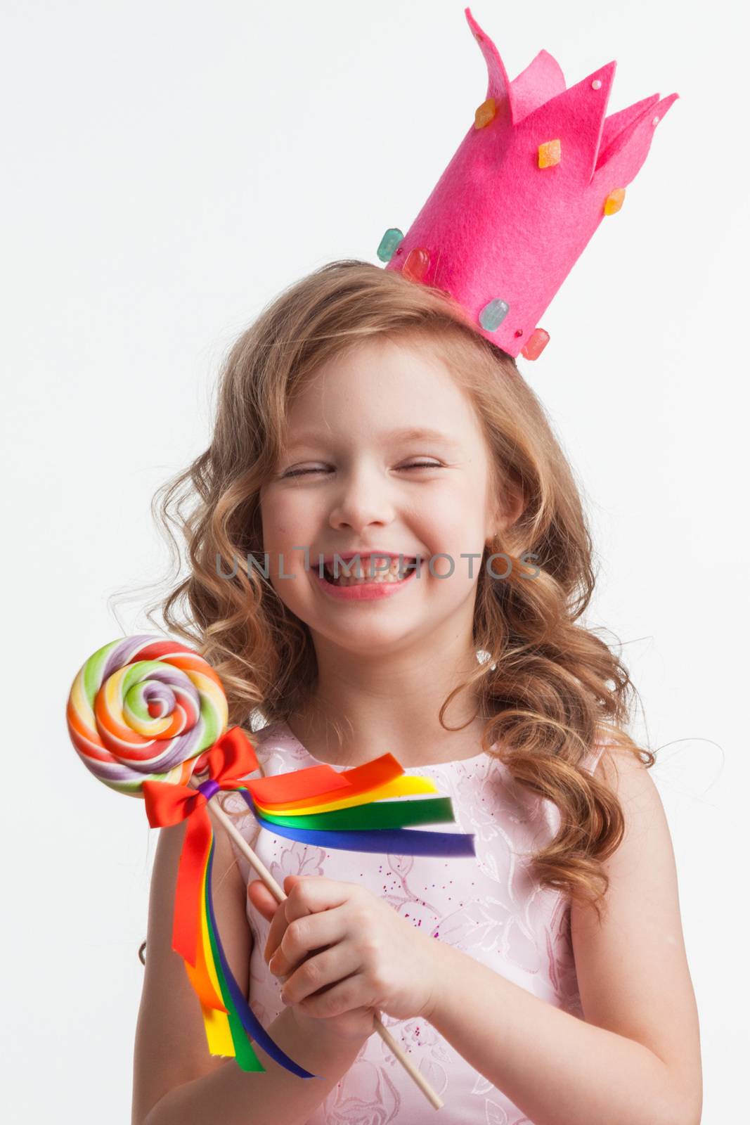 Beautiful little candy princess girl in crown holding big lollipop and laughing