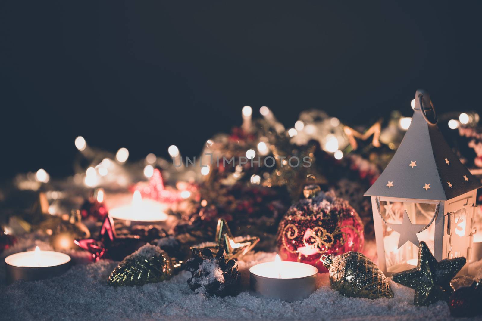Lantern and christmas decoration on snow and garland lights background