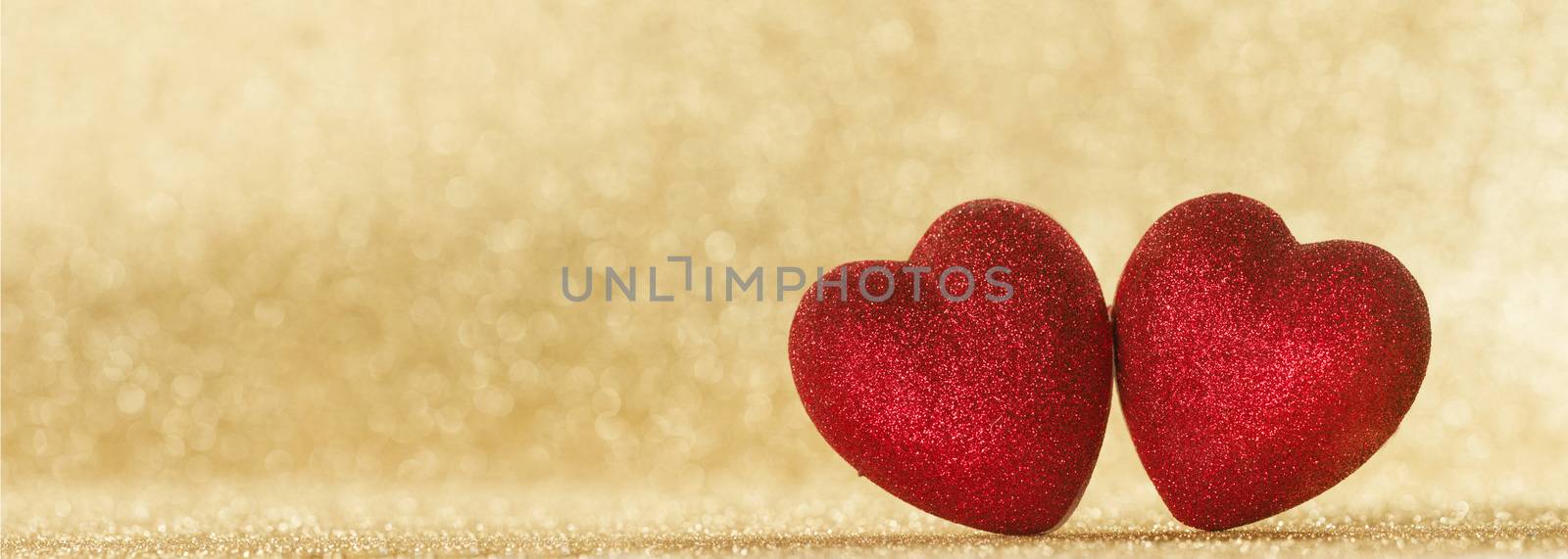 Two small handmade red glitter hearts on bright golden lights bokeh background Valentines day card