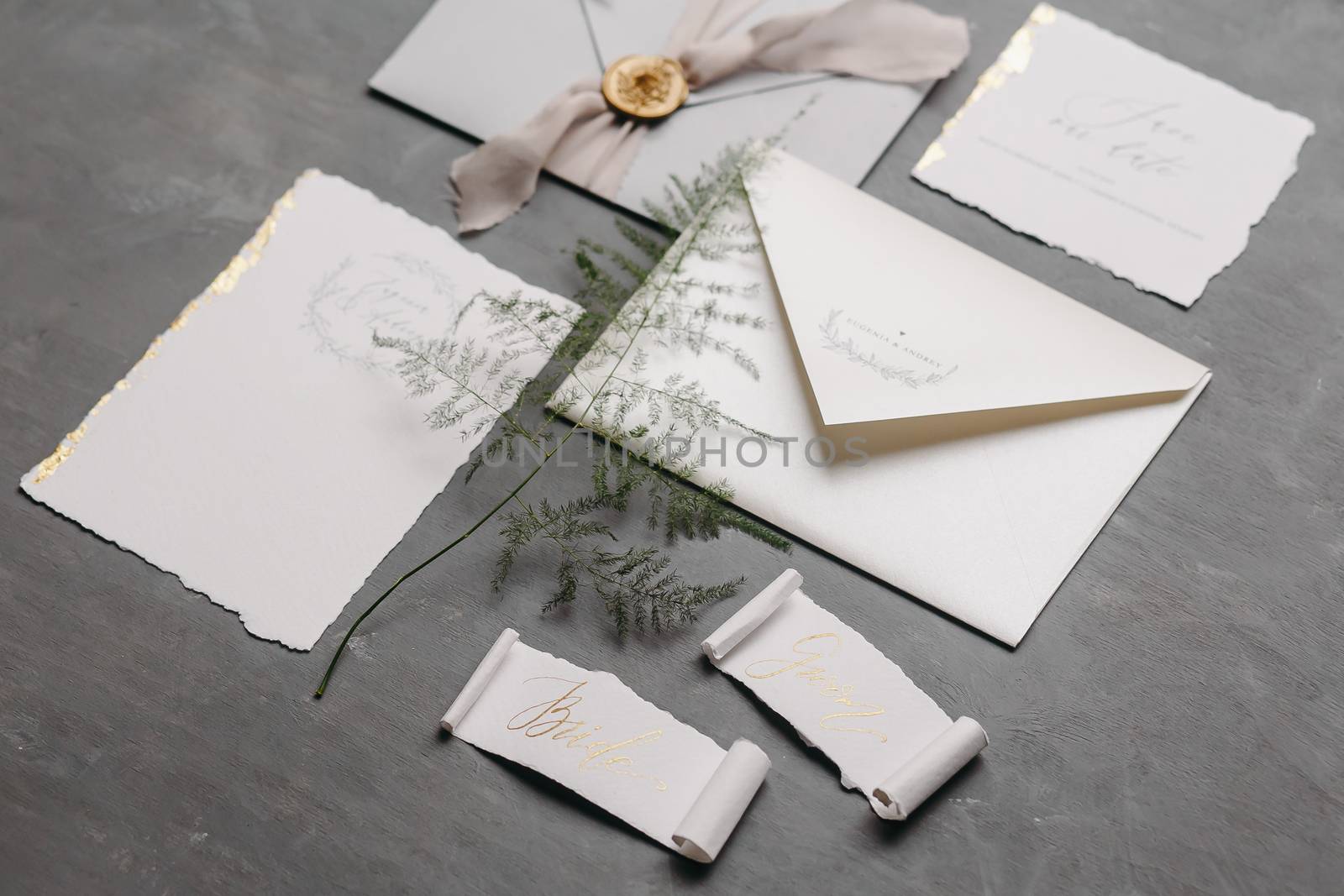 Wedding details flat lay. Wedding invitation and scroll paper. Bottle with fragrance. Simple bouquet. Ring box.